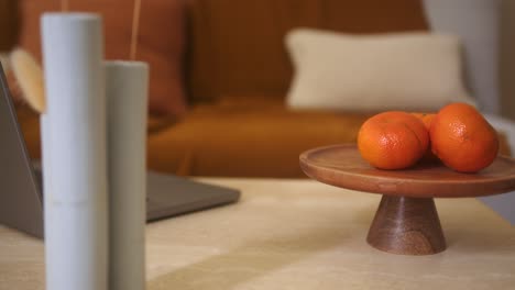 Orangen-Auf-Holzständer-Mit-Hohen-Vasen-Und-Laptop