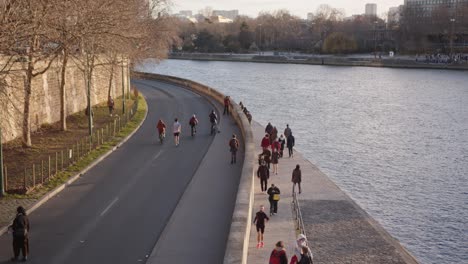 Peatones-Caminando-Y-Corriendo-A-Lo-Largo-Del-Paseo-Junto-Al-Río-Sena-En-París,-Francia