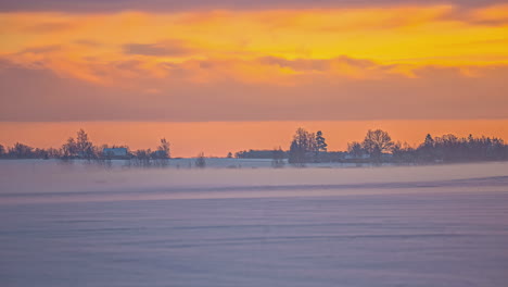 Winter-rural-time-lapse-moving-clouds-in-golden-sky-in-foggy-morning,-rural-Latvia