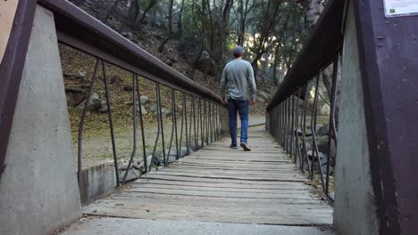 Ein-Mann-Wandert-über-Eine-Brücke-Und-Bleibt-Stehen,-Um-Die-Aussicht-Zu-Genießen