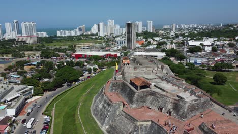 Aerial-Birds-Eye-Approach-Flying-Towards-The-Colombian-Flag-Waving-Over-An-Old-Historic-Colombian-City-Fortress-In-Cartagena,-Colombia