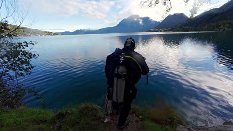 A-diver-gets-ready-and-jumps-into-a-beautiful-lake-with-mountains-in-the-background