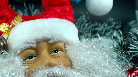 Detailed-close-up-smooth-tilt-up-shot,-happy-Santa-Claus-toy-in-a-red-hat-with-bells,-Christmas-decoration,-traditional-holiday-presents,-new-year-decor,-shiny-colorful-gifts,-4K-video