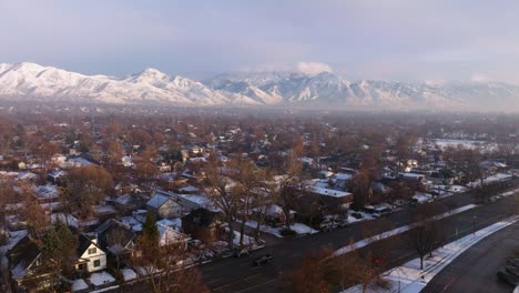 Drone-dolly-above-large-arterial-roadway-and-suburbs-with-Wasatch-mountain-ridgelines-covered-in-snow