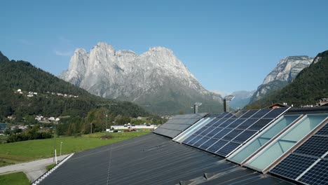 Industriefabrik-Mit-Sonnenkollektoren-Für-Erneuerbare-Energien-Auf-Dem-Dach,-Berge-Im-Hintergrund