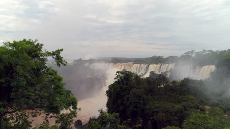 Drone-emerging-from-behind-trees,-unveiling-the-breathtaking-Iguazu-Falls