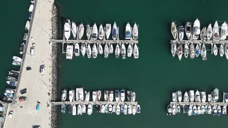 Aerial-bird's-eye-view-of-sailboats,-yachts,-and-fishing-vessels-docked-at-new-concrete-pier