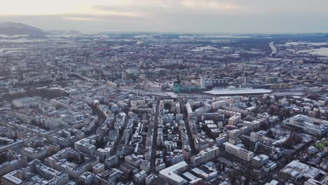 Aerial-of-Salzburg-cityscape,-flying-above-buildings,-snow-white-city-winter