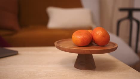 Orangen-Auf-Einem-Holzständer-Auf-Einem-Couchtisch-In-Einem-Warmen,-Gemütlichen-Zuhause