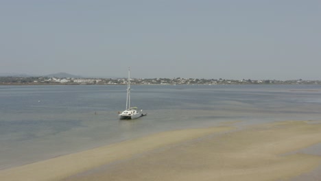 Catamaran-Boat-Floating-Near-The-Shore-Of-Beach-In-Armona-Island,-Algarve,-Portugal