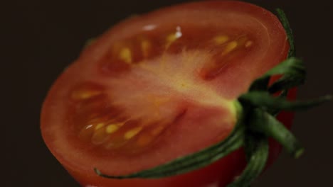 Drehen-Der-Hälften-Frischer,-Reifer,-Geschnittener-Tomaten-Auf-Dunklem-Hintergrund