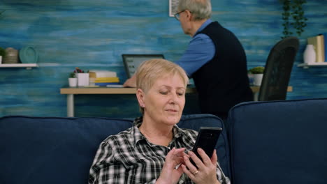 Nette-ältere-Dame,-Die-Auf-Der-Couch-Ruht-Und-Anwendungen-Auf-Dem-Smartphone-Nutzt