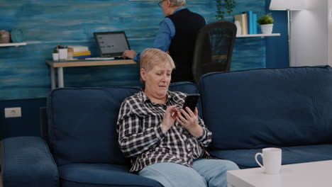 Middle-aged-woman-relaxing-holding-smartphone-reading-news