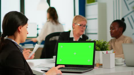 über-Der-Schulter-Eines-Managers,-Der-Am-Besprechungstisch-Sitzt-Und-Auf-Einen-Laptop-Mit-Grünem-Bildschirm-Schaut