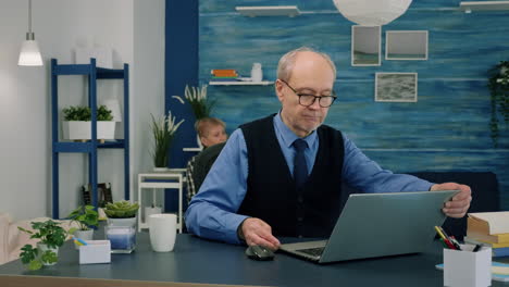 Senior-remote-businessman-opening-laptop-and-reading-reports