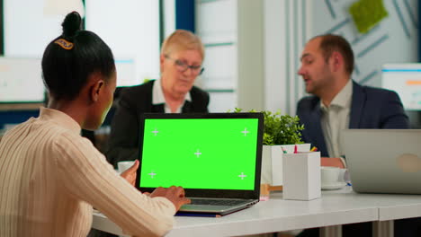 African-manager-woman-sitting-at-conference-desk-looking-at-laptop-with-green-screen