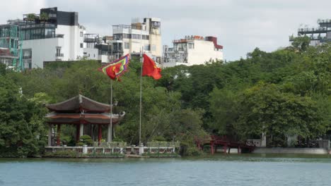 Ondean-Banderas-Nacionales,-El-Templo-Ngoc-Son,-El-Lago-Hoan-Kiem,-En-El-Centro-De-Hanoi,-Vietnam