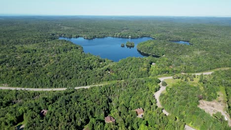 Rising-drone-shot-of-lake-being-revealed-in-the-distance-surrounded-by-green-forest