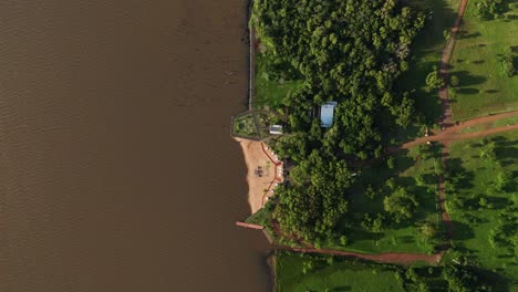 Zenithal-drone-view-of-a-private-beach-along-the-Paraná-River,-Argentina,-showcasing-an-exclusive-riverside-retreat-with-pristine-sands-and-breathtaking-river-vistas
