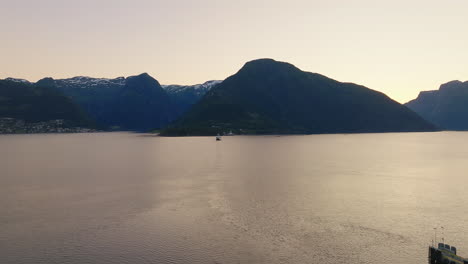 Ferry-transports-passengers-across-Sognefjorden-Fjord-at-dusk-in-Norway,-aerial
