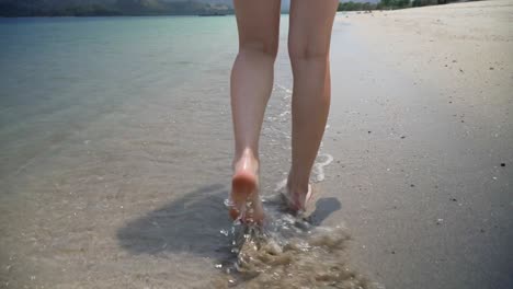 Close-Up-Slow-Motion-Shot-of-Female-Legs-and-Feet-Walking-Through-Shallow-Water-on-Tropical-Beach