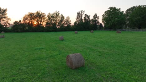 Sonnenuntergang-über-Einem-Feld-Mit-Verstreuten-Heuballen-Und-Bäumen