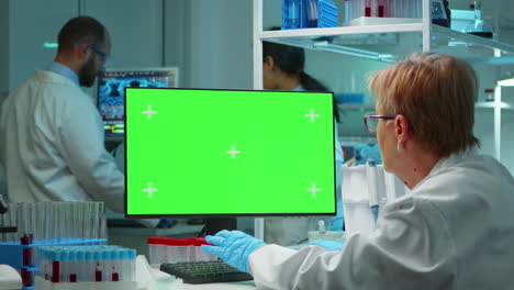 Senior-doctor-working-at-computer-with-green-screen