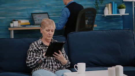 Middle-aged-old-woman-relaxing-holding-tablet-reading-e-book