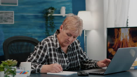Old-woman-entrepreneur-checking-financial-project-taking-notes
