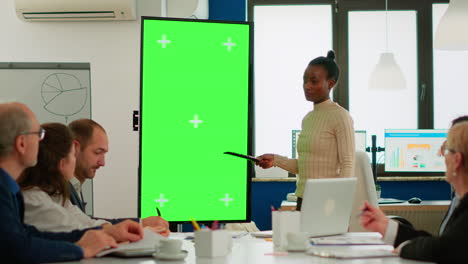 African-businesswoman-analysing-annual-reports-pointing-at-green-screen-monitor