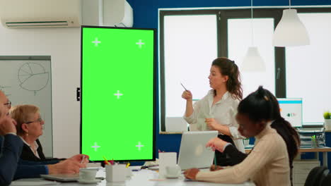 Leader-briefing-businessteam-standing-in-meeting-room-showing-at-greenscreen-display