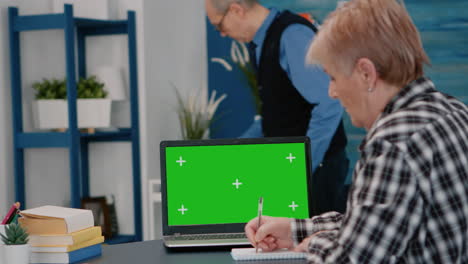 Elderly-person-reading-on-green-screen,-mock-up,-chroma-key-display-of-laptop