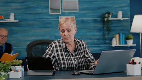 Multitasking-Frau-Im-Ruhestand,-Die-Gleichzeitig-Auf-Laptop-Und-Tablet-Liest