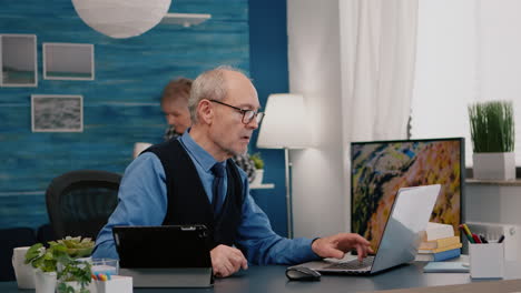 Senior-man-using-laptop-and-tablet-in-same-time