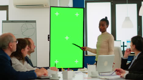 Diverse-woman-standing-in-start-up-office-discussing-strategy-with-green-screen-display