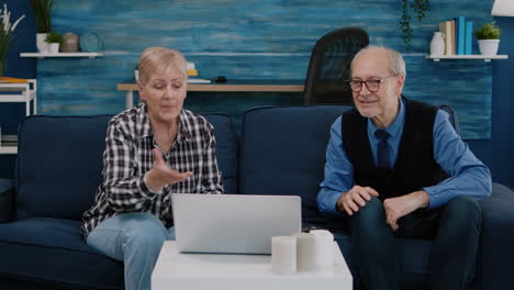 Lächelndes-älteres-Paar,-Das-Während-Des-Videoanrufs-Auf-Den-Laptop-Schaut-Und-Winkt