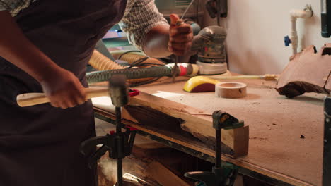 Manufacturer-shaping-raw-timber-using-chisel-and-hammer,-creating-wood-art