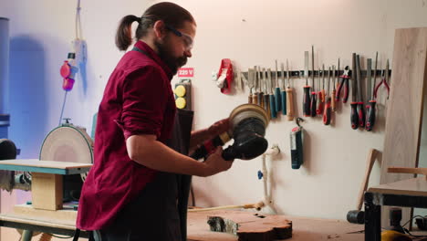 Man-with-protective-glasses-uses-orbital-sander-gear-after-consulting-schematics