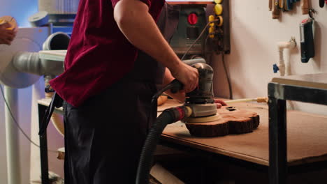 Woodworking-expert-in-carpentry-shop-using-angle-grinder-to-fix-wooden-surface