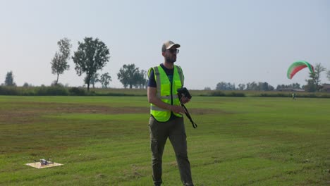 A-Man-in-a-Safety-Vest-is-Getting-the-Drone-Ready-for-Flight-on-the-School-Grounds---Slow-Motion