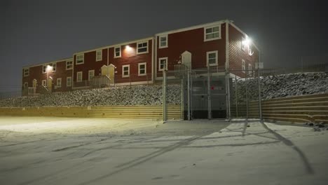 Red-building-outside-at-night-with-snow-blowing