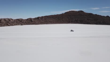 Tracking-shot-of-a-vehicle-driving-past-an-island-in-the-middle-of-the-Bolivian-Salt-Flats