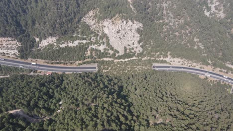 Vista-Por-Drones-Del-Tráfico-De-Vehículos-En-La-Carretera-Y-El-Túnel-Construido-Entre-Las-Montañas,-Transporte-Interurbano
