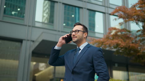Happy-Businessman-Talking-on-Phone-Standing-Outside-Against-Corporate-Building---slow-motion-parallax
