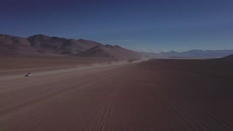 Aerial-shot-of-vehicles-traversing-through-the-Salvador-Dalí-Desert-in-Bolivia