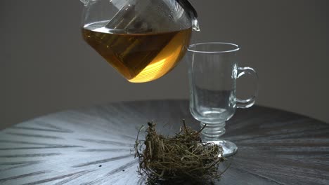 Pouring-cerasee-tea-in-glass-kerala-bitter-melon-plant-with-kerala-hanging-from-vines-used-to-make-herbal-healthy-tea-good-for-weight-loss