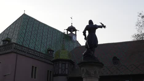 Close-up-view-of-the-Schwendi-fountain-statue-monument-and-a-half-timbered-medieval-building-in-the-historic-town