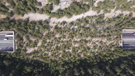 Vista-Por-Drones-Del-Tráfico-De-Vehículos-En-La-Carretera-Y-El-Túnel-Construido-Entre-Las-Montañas