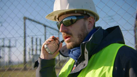 Male-engineer-listening-to-the-walkie-talkie-while-nodding-his-head,-handheld-closeup