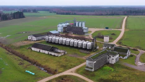 Modern-farm-with-shiny-grain-silos-on-an-overcast-day,-drone-view
